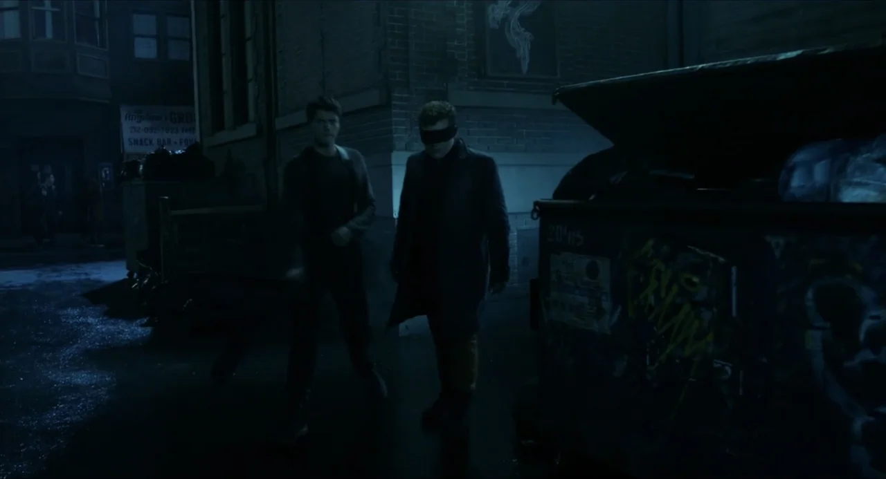 Henry Danger: The Movie (2025) movie still: fullbody — A dark, damp urban alleyway at night features brick buildings and a large dumpster. Two men…