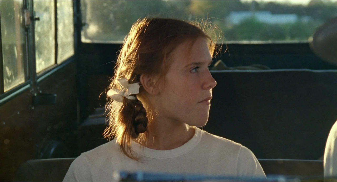 Lolita (1997) movie still: closeup — The interior of a vehicle during golden hour with light streaming through the window. A young girl with braided…