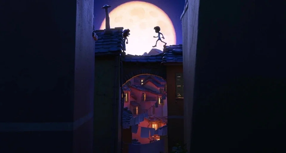 Luca (2021) movie still: wide — A dense cluster of Mediterranean-style buildings is illuminated by the glow of a full moon. Two small figures are…