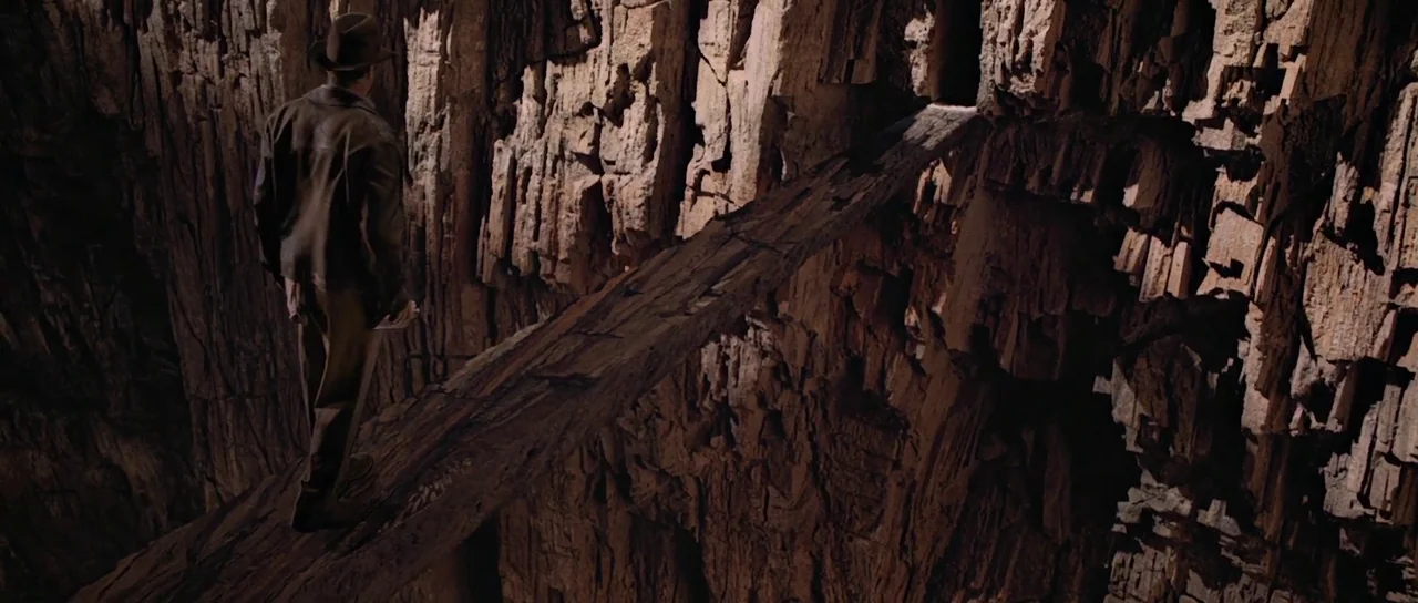 Indiana Jones and the Last Crusade (1989) movie still: fullbody — A deep rocky canyon with vertical stone layers and a narrow makeshift wooden…