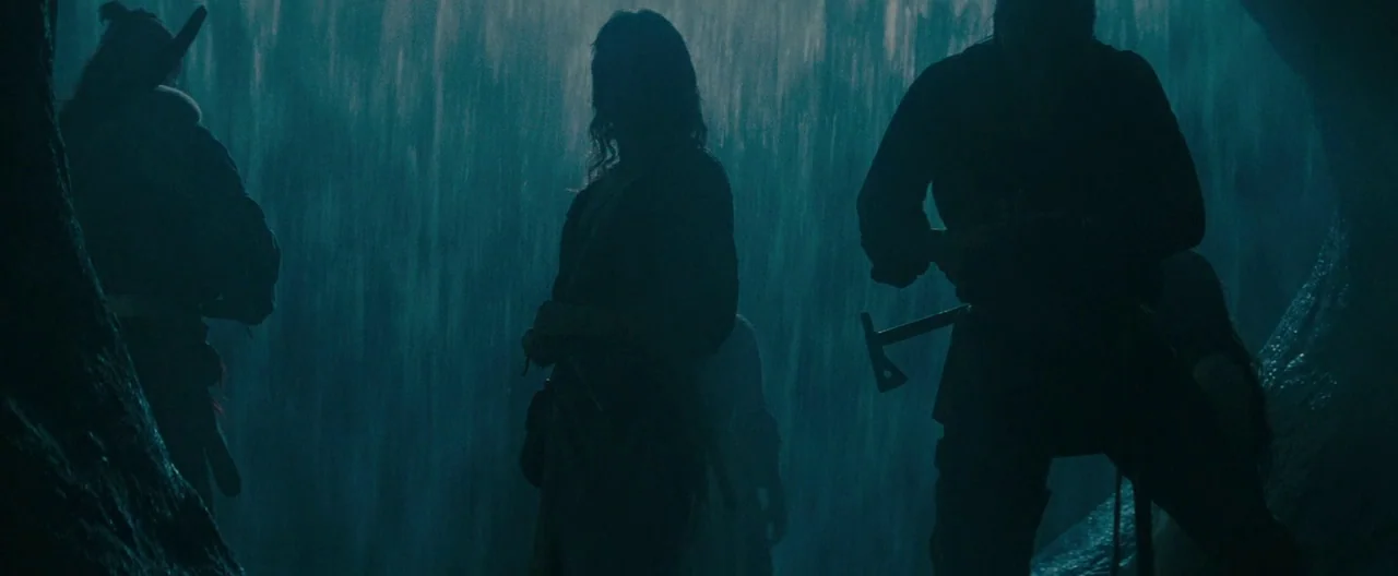 The Last of the Mohicans (1992) movie still: wide — A group of people stands behind the veil of a massive, roaring waterfall. The figures are…