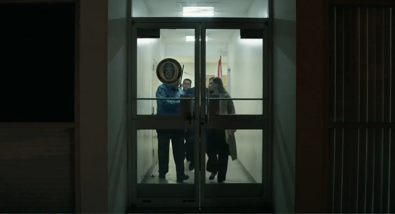 Ted Bundy: American Boogeyman (2021) movie still: medium — A long institutional hallway with white walls viewed through a set of glass doors. A…