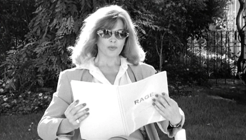 The Tango Lesson (1997) movie still: medium — A woman sits in a leafy yard surrounded by dense trees and greenery. She holds an open script with the…