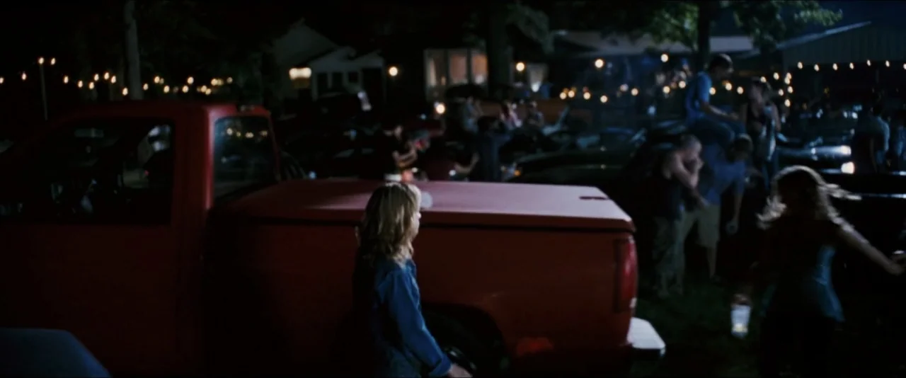 Black Snake Moan (2006) movie still: medium — A dark outdoor parking lot at night contains a large red pickup truck. A young blonde woman in a blue…