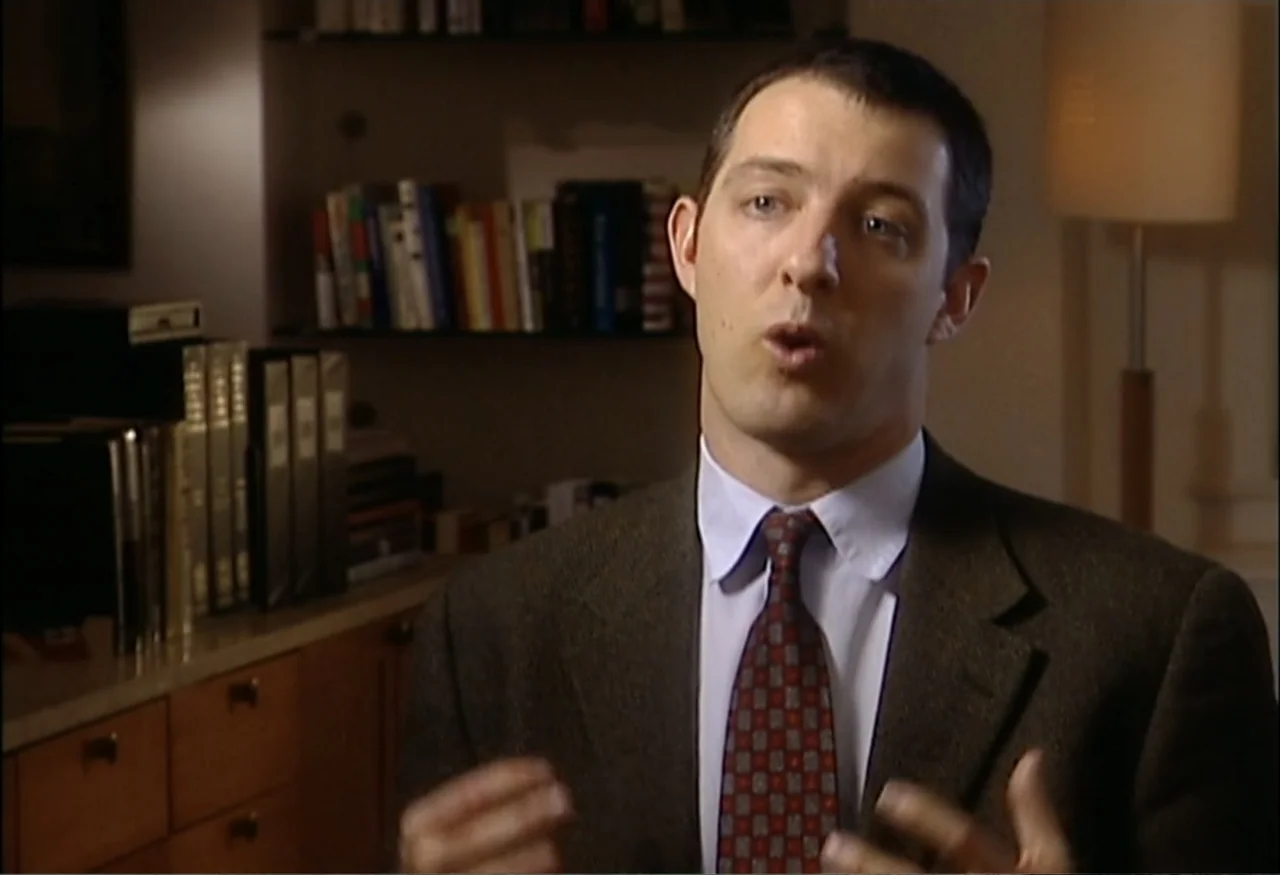 Indian Point: Imagining the Unimaginable (2004) movie still: medium — An interior home office contains a bookshelf and a floor lamp. A man wears a…