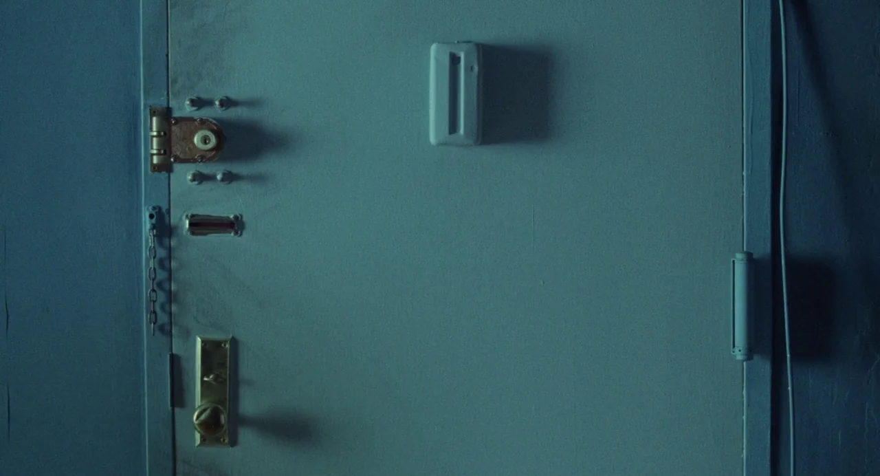What Happened Was… (1994) movie still: closeup — A flat-surfaced door features a central latch and a standard brass lock mechanism. The blue-painted…