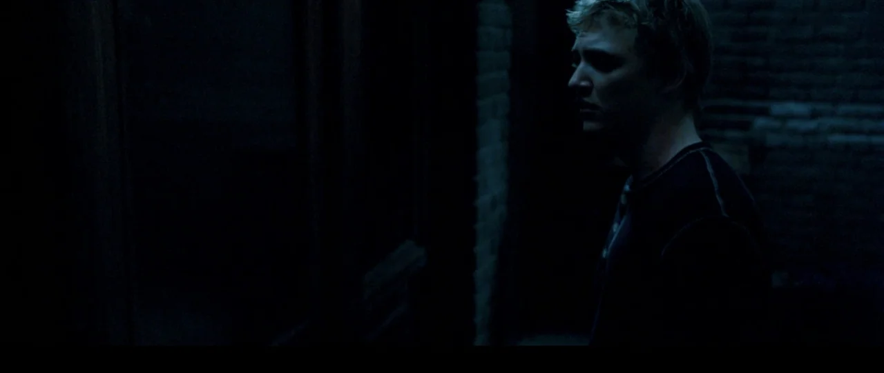 The Haunting in Connecticut (2009) movie still: medium — A dark brick alleyway at night with deep shadows obscuring the surroundings. A young man…