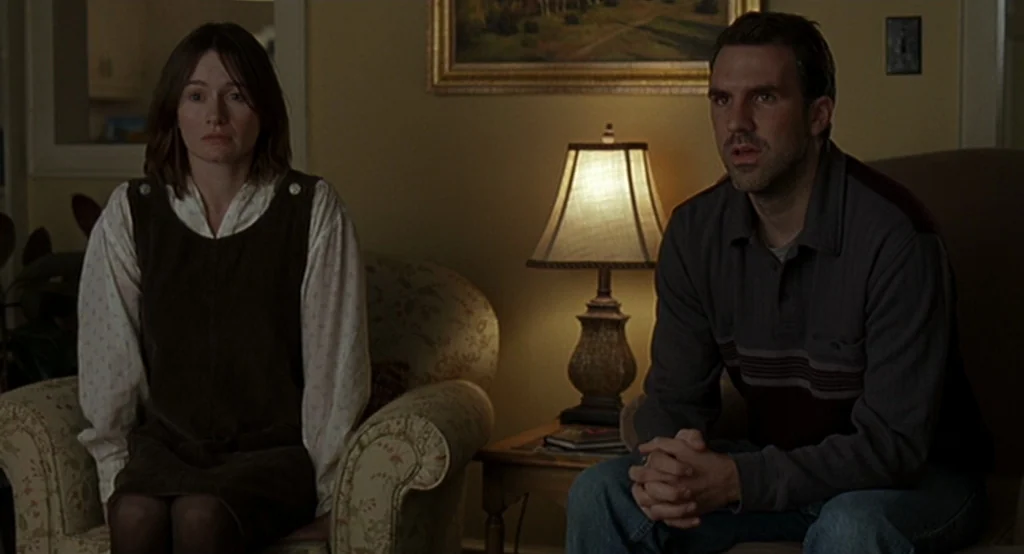 Lars And The Real Girl (2007) movie still: medium — A dimly lit room with yellow walls contains a table lamp and framed landscape painting. A man…
