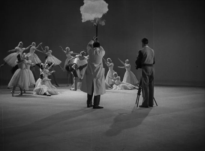Summer Interlude (1951) movie still: wide — A spacious film studio with a plain, neutral-toned floor and a dark, empty background. A film crew…