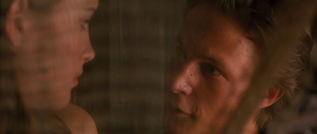 Stealing Beauty (1996) movie still: closeup — A dimly lit room provides a background for two individuals standing in close proximity. A man in the…