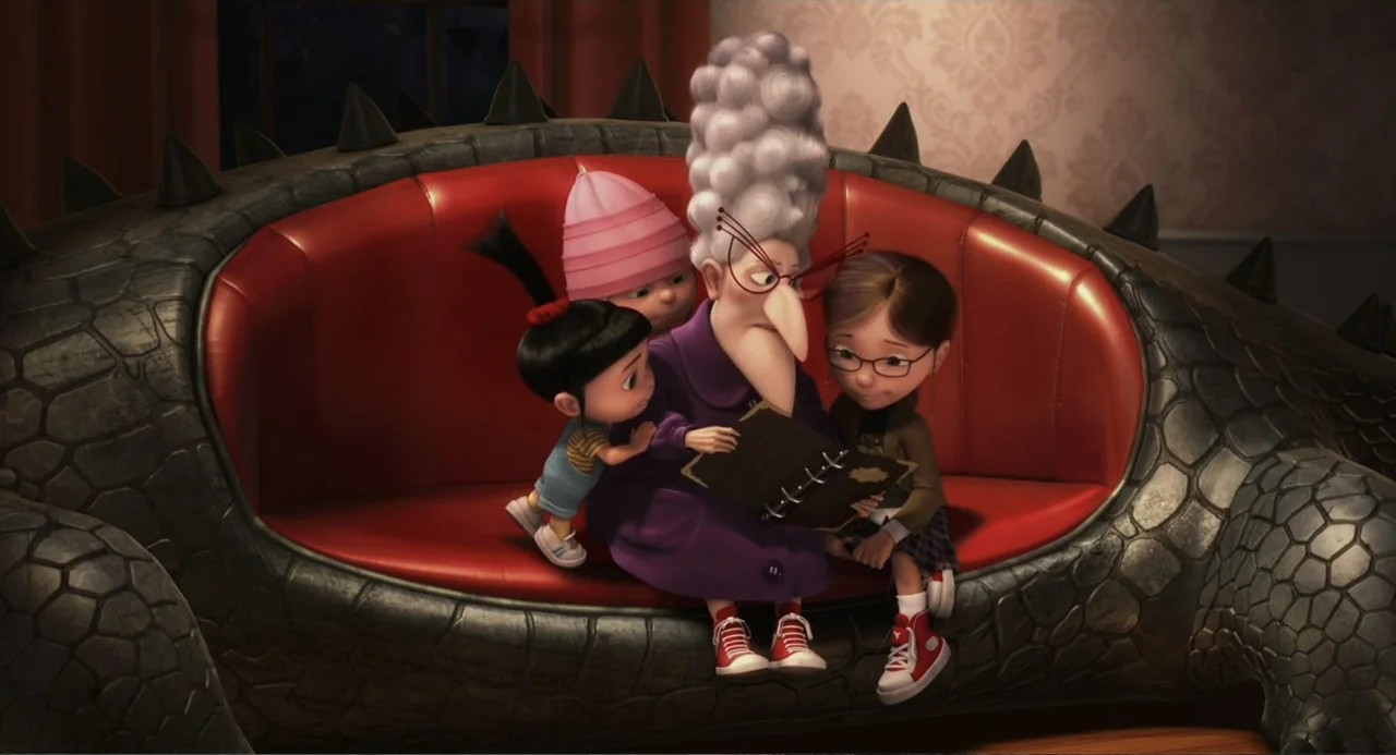 Despicable Me (2010) movie still: medium — An elderly woman sits on a reptilian-shaped red sofa reading to three young children. The group is…