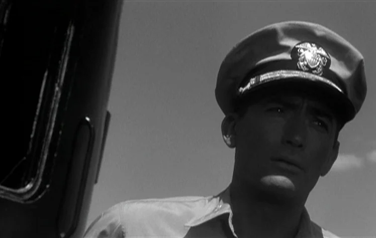 On The Beach (1959) movie still: closeup — A man in a naval officer uniform stands on the deck of a ship. He is looking away from the camera toward…