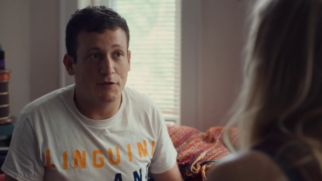 Saint Frances (2019) movie still: medium — A residential room features a window with closed horizontal blinds and a textured throw blanket. A young…