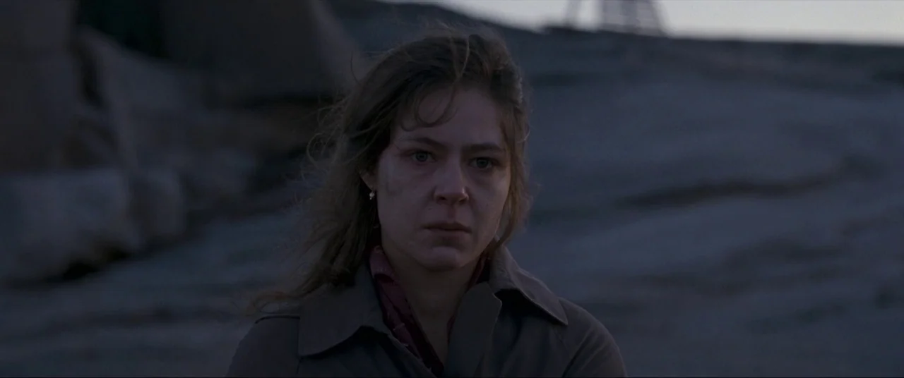 Leviathan (2014) movie still: closeup — A rocky, barren outdoor landscape is seen under the low light of evening. A young woman with wind-swept hair…