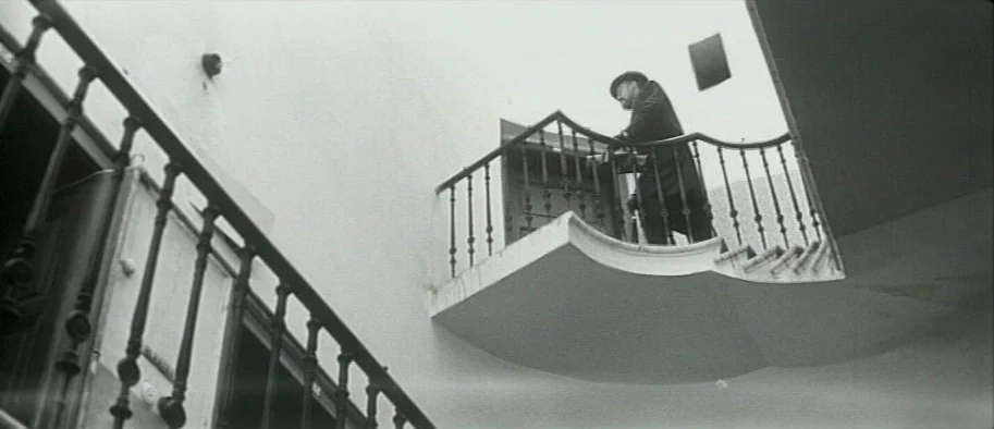 And The Fifth Horseman is Fear (1965) movie still: wide — A stark white outdoor stairwell features minimalist concrete landings and black metal…