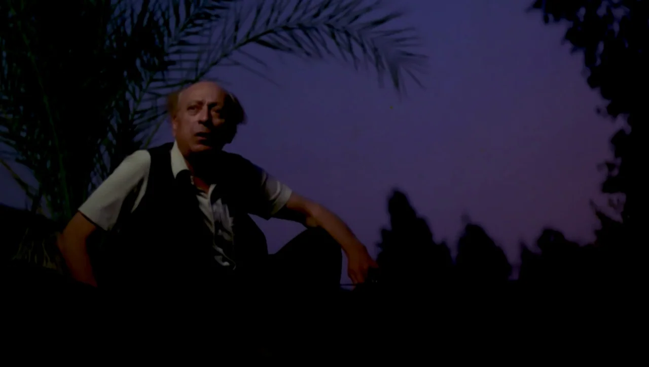 The Return of the Prodigal Son (1978) movie still: medium — An elderly man sits low in a field under a darkening evening sky. The background…