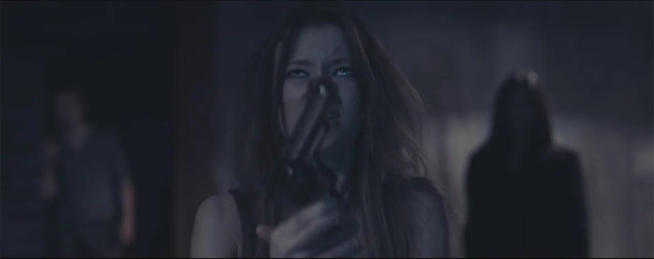 El Último Juego (2025) movie still: medium — A dimly lit interior space contains a woman holding a pistol. She looks directly forward while out of…