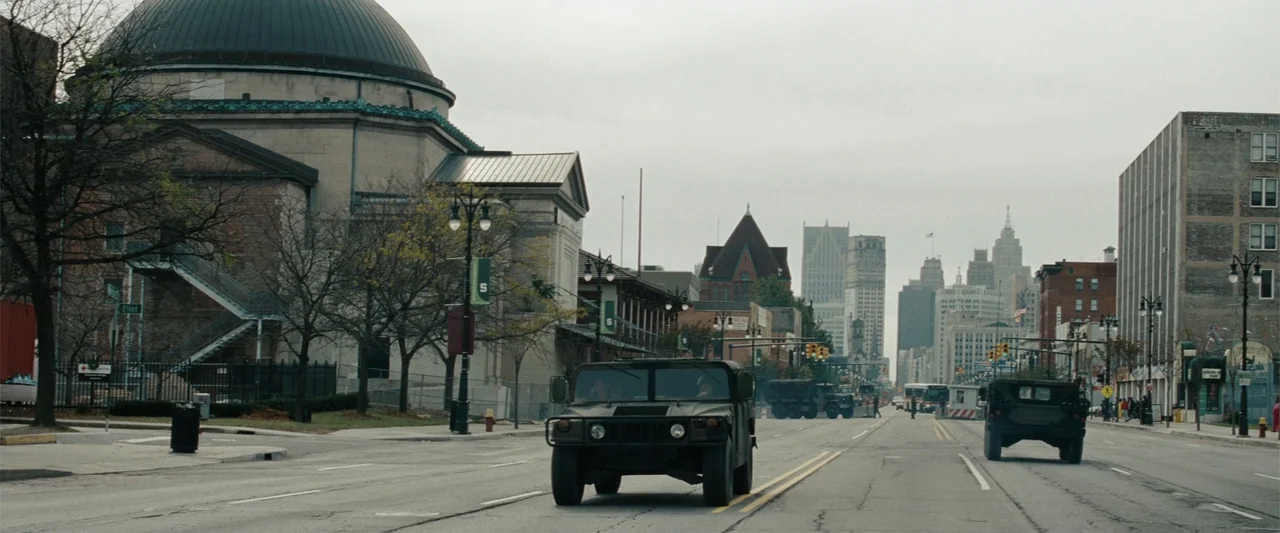 Red Dawn (2012) movie still: wide — A wide city street features a large domed stone building and distant skyscrapers under overcast. Military…