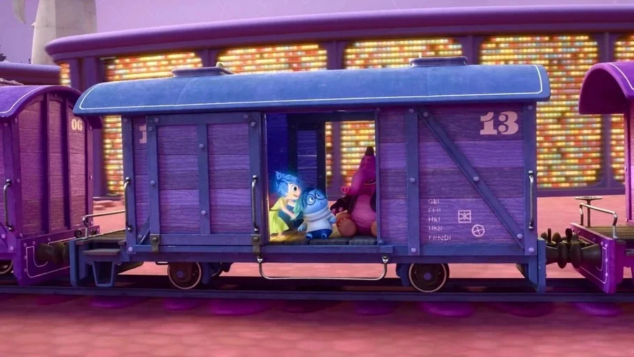 Inside Out (2015) movie still: wide — A purple wooden train car moves through a landscape filled with glowing multi-colored lights. Three animated…
