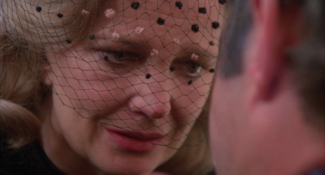 Opening Night (1977) movie still: closeup — A woman wears a black mourning veil in an outdoor setting. She gazes toward another person whose head is…