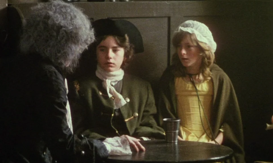 Black Jack (1979) movie still: medium — An 18th-century tavern interior features dark wood paneling and simple wooden furniture. Two young people…