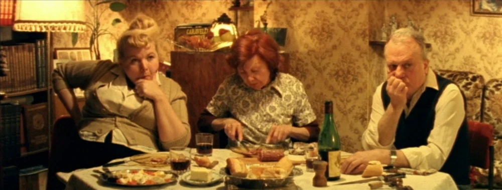 I Stand Alone (Seul Contre Tous) (1998) movie still: medium — A 1970s dining room features floral wallpaper and a table laden with food. Three…