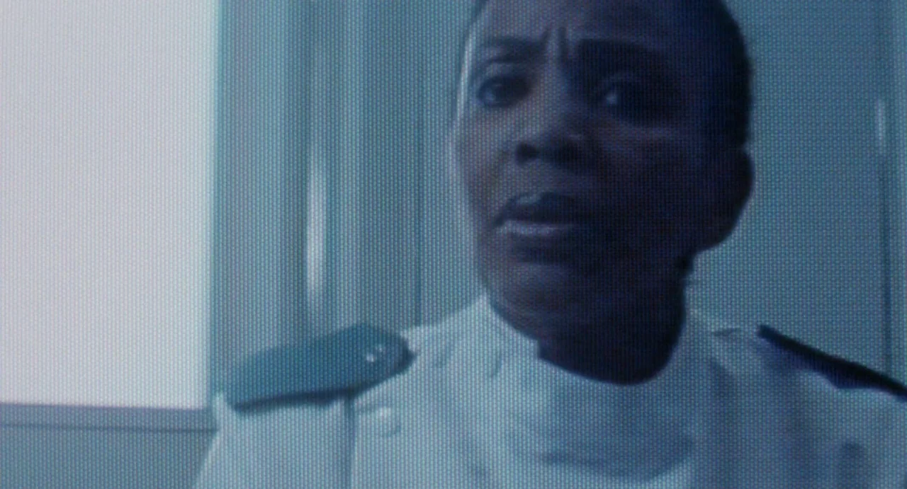 Aliens (1986) movie still: closeup — A person stands indoors near a window with bright daylight filtering through the pane. The individual stares…