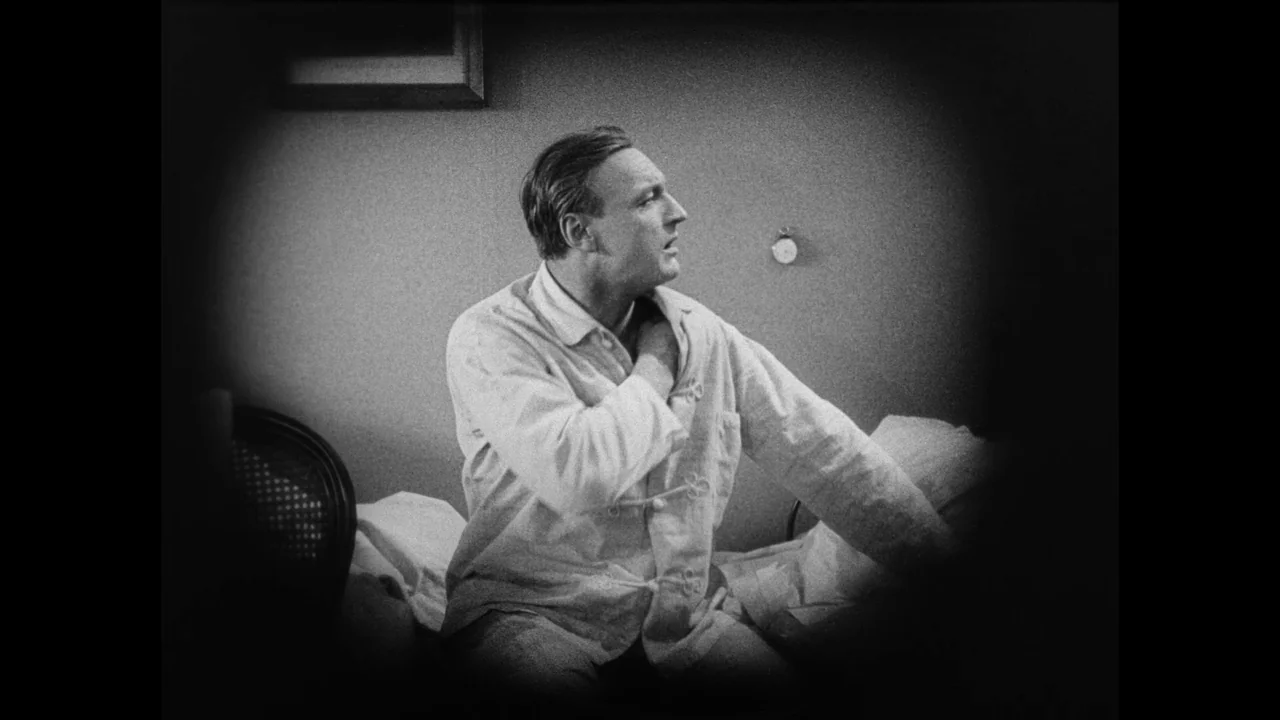 Master of the House (1925) movie still: medium — A dark, sparsely furnished space with a plain wall and a framed object. A man in light-colored…