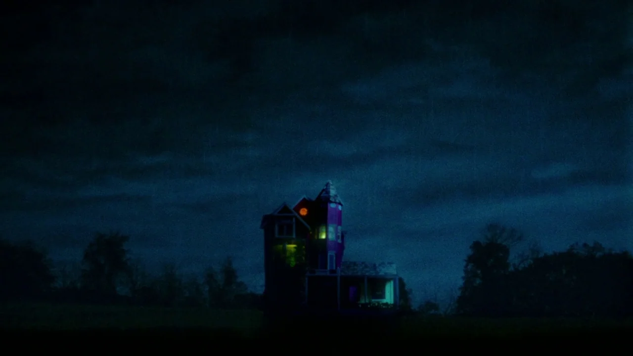 Strawberry Mansion (2021) movie still: establishing — A dark house with a prominent tower sits isolated against a deep blue night sky. Internal…