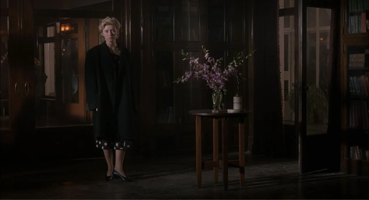 Wild Orchid II: Two Shades of Blue (1991) movie still: fullbody — A dark, wood-paneled room contains floor-to-ceiling glass-fronted bookshelves and…