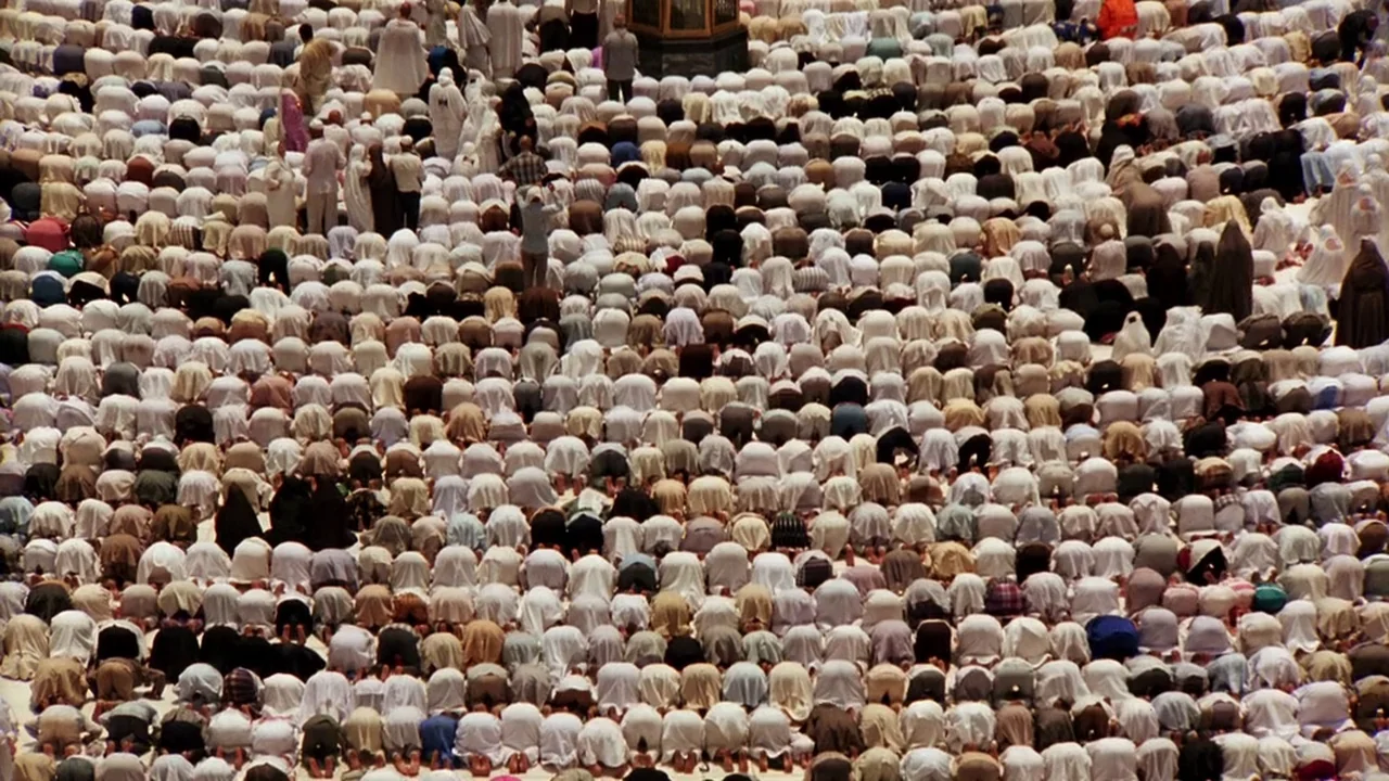 Malcolm X (1992) movie still: wide — A vast crowd of people are kneeling in unison within a large outdoor space. The individuals are mostly dressed…