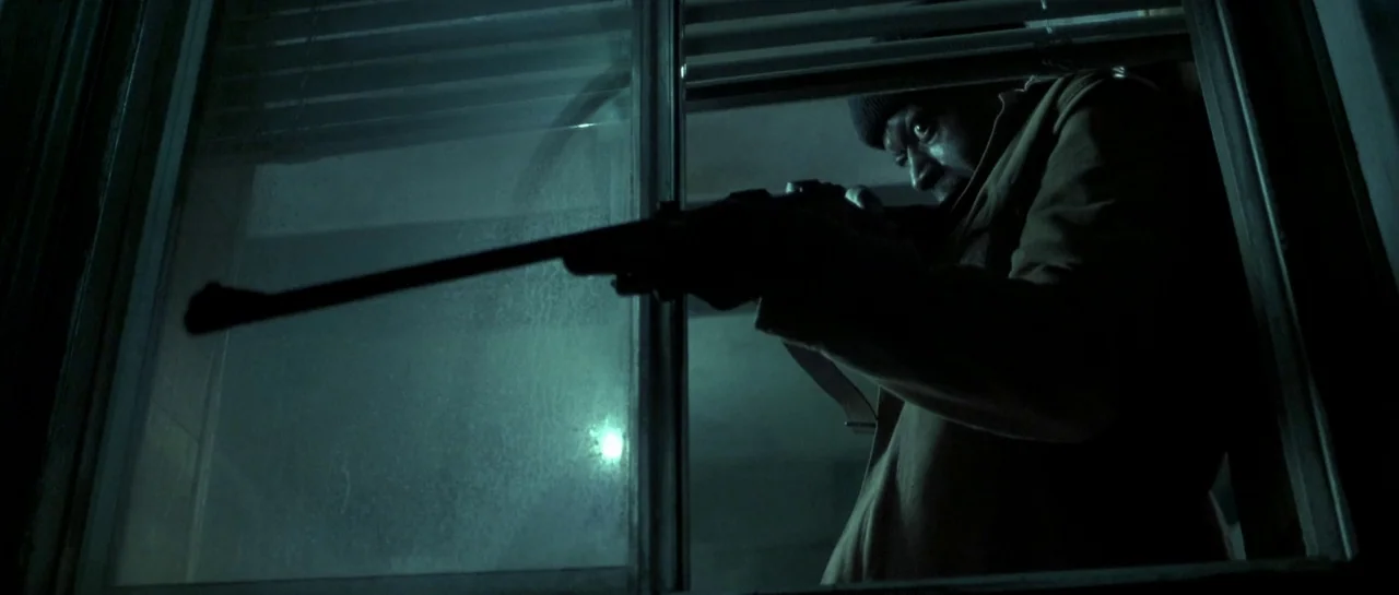 Bones movie still: medium — A man looks through an open window at night into a dark urban environment. He aims a long rifle towards the outside…