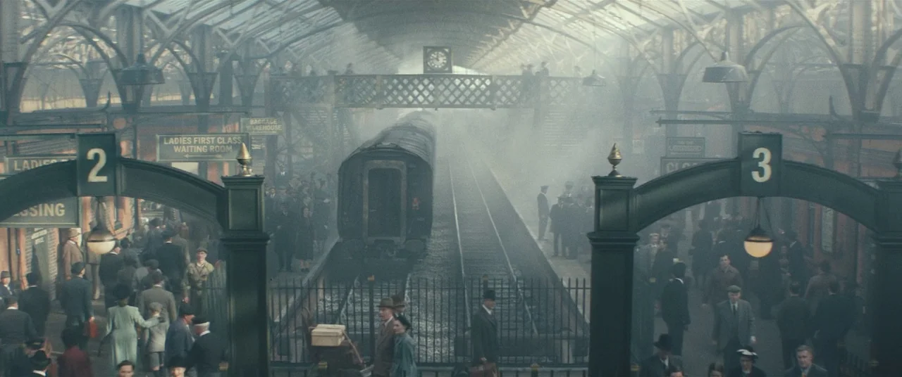 Christopher Robin (2018) movie still: establishing — A busy, smoky Victorian-style train station terminal features high iron arches and glass…