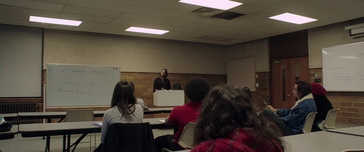 It Follows (2015) movie still: wide — A dimly lit room with brick walls and fluorescent lights serving as a classroom. An instructor stands at a…