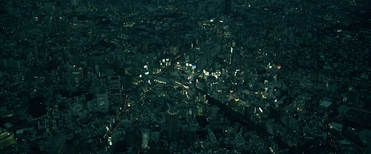Resident Evil: Afterlife (2010) movie still: establishing — A high-altitude aerial view of a dense, sprawling metropolis illuminated by scattered…