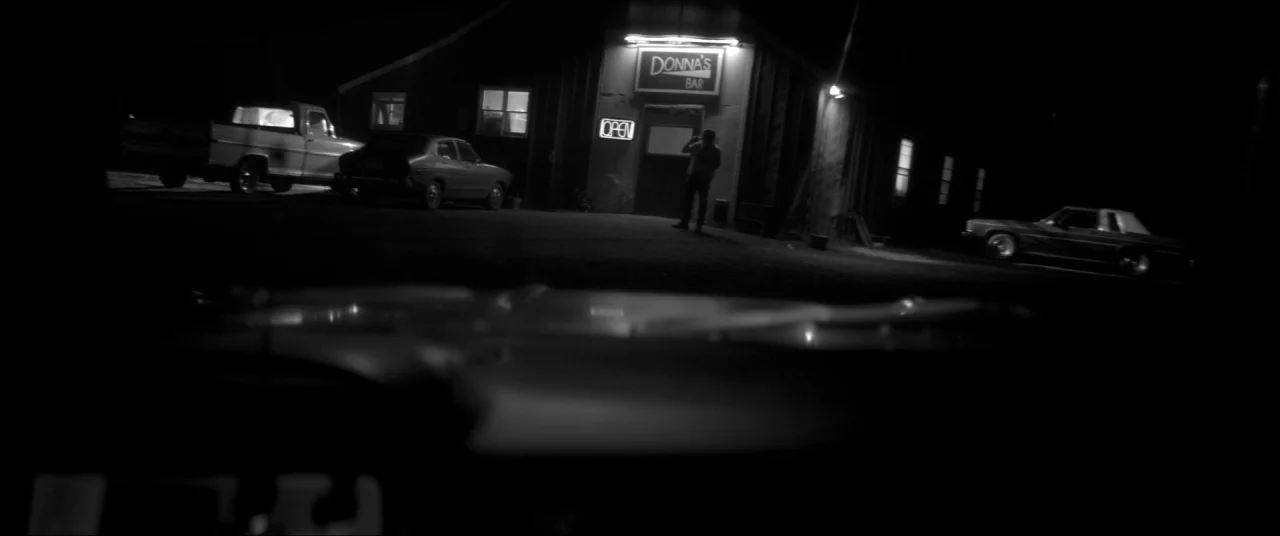 The Eyes of My Mother (2016) movie still: wide — A dark, rural parking lot outside a wooden building identified as Donna's Bar. A lone person stands…