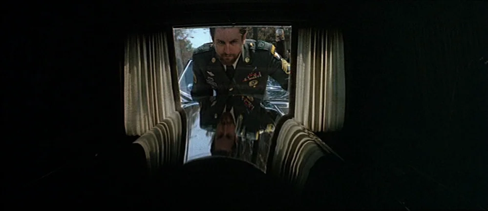 The Deer Hunter (1978) movie still: medium — Inside a dark vehicle, the rear glass window opens to reveal an exterior view. A man in a military…