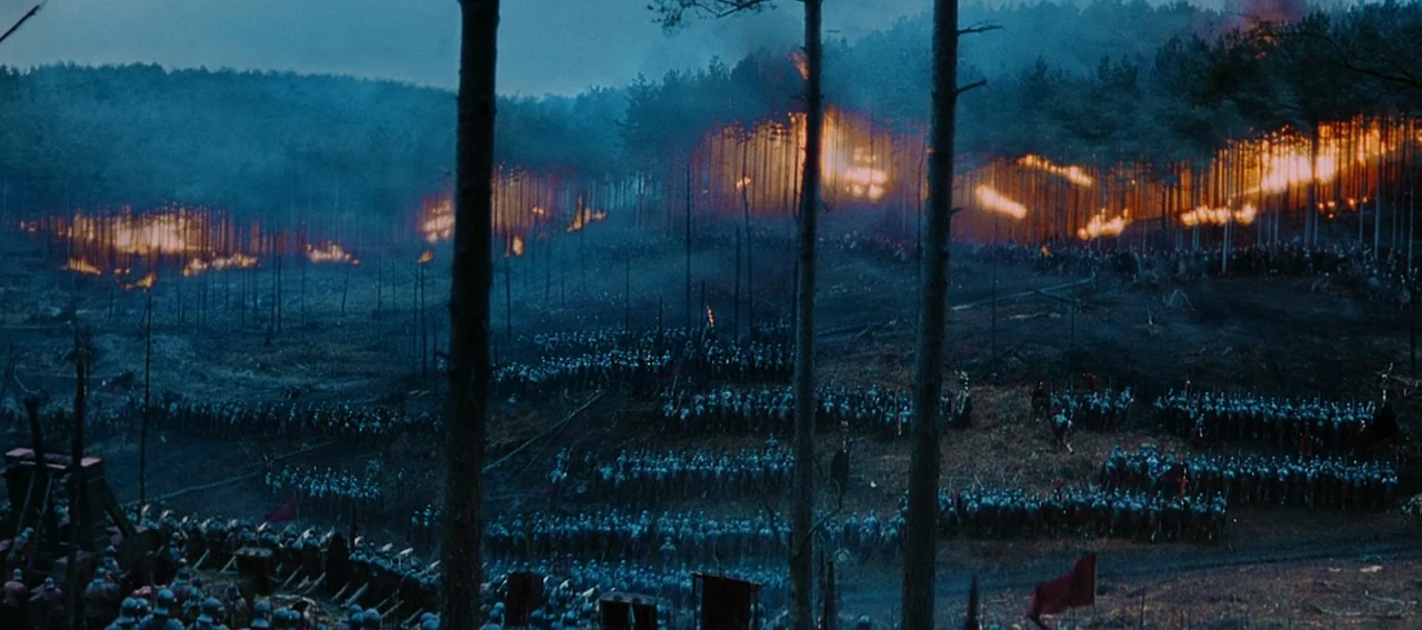 Gladiator (2000) movie still: establishing — A dark, hilly battlefield at night is illuminated by a row of burning trees. Hundreds of armored…