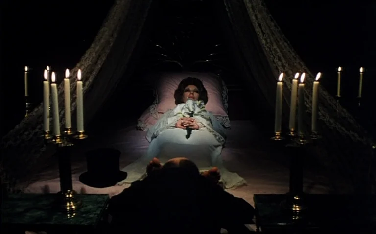 Business is Business (1971) movie still: medium — A dark, candlelit room features a woman lying centered on a large canopy bed. She rests with her…