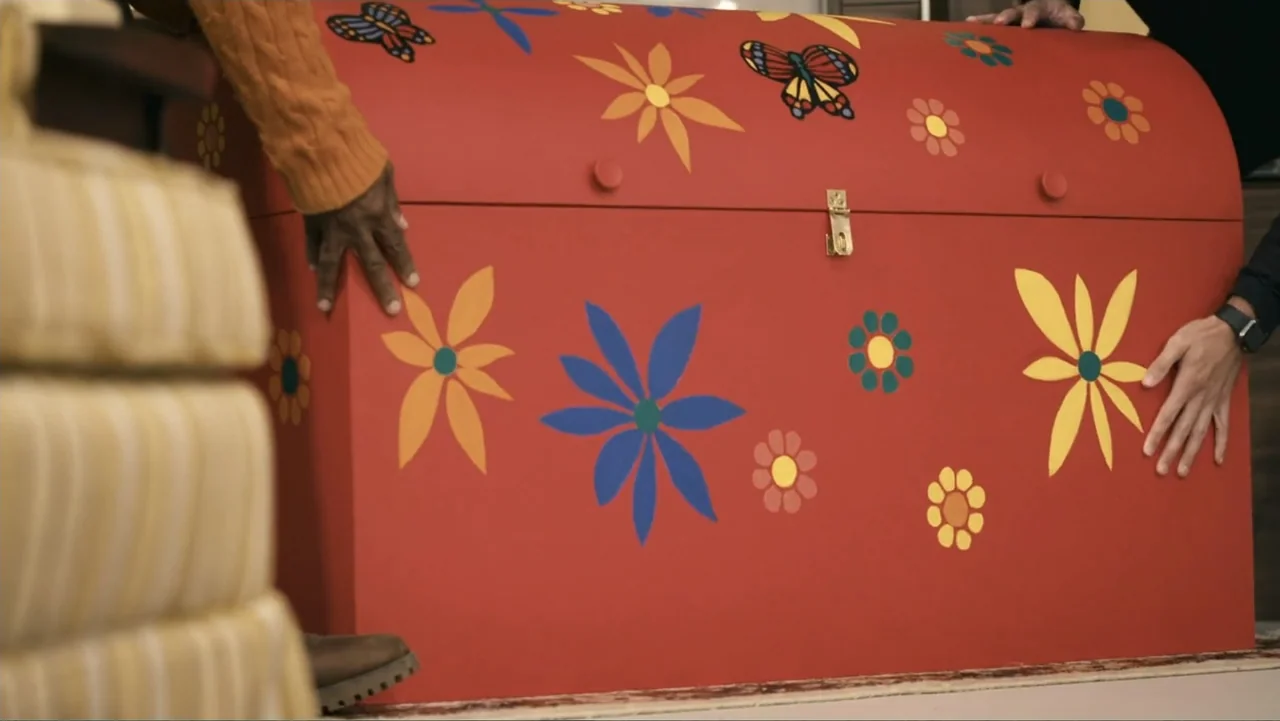 Mr. Dressup: The Magic of Make Believe (2023) movie still: medium — A living room interior featuring a large red wooden chest decorated with painted…