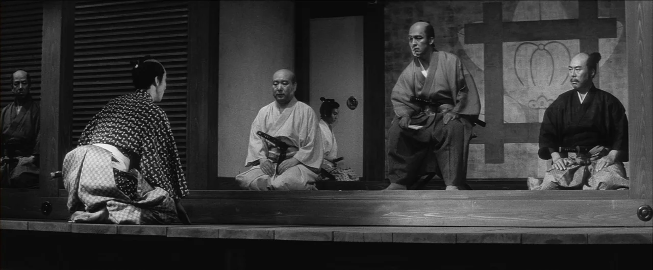 Harakiri (1962) movie still: wide — A traditional Japanese interior with wooden floors and sliding panels in the background. Several men dressed in…