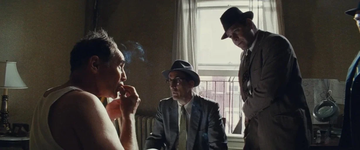 Bridge of Spies (2015) movie still: medium — An interior room with dim lighting features a window covered by sheer white curtains. Three men in…