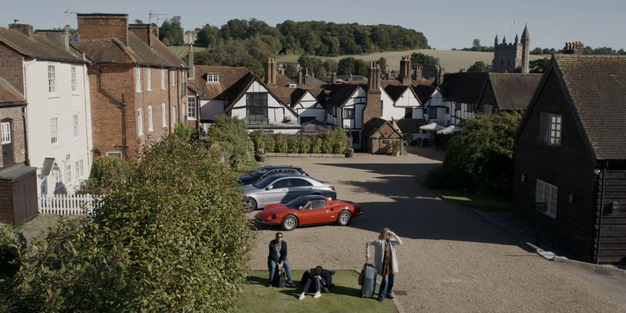The People We Hate at the Wedding (2022) movie still: wide — A gravel courtyard in a rural English village features historic half-timbered brick…