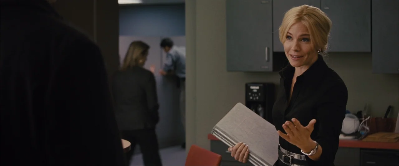 Unfinished Business (2015) movie still: medium — A modern office space features grey cabinetry, red chairs, and cubicle partitions. A blonde woman…