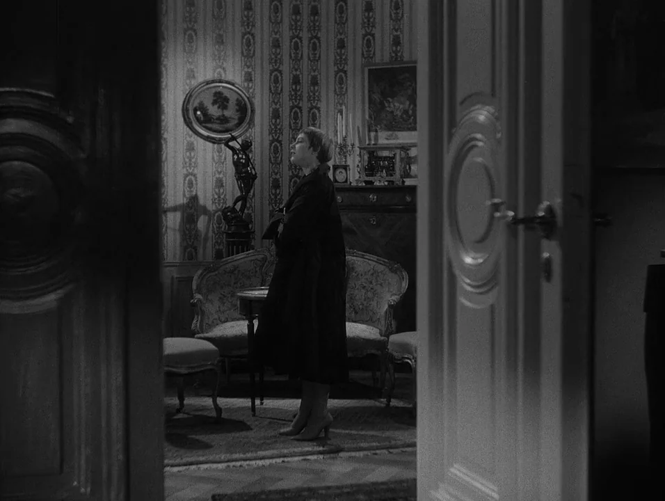 Dreams (1955) movie still: medium — A dimly lit room features patterned wallpaper, ornate vintage furniture, and a decorative circular mirror. A…