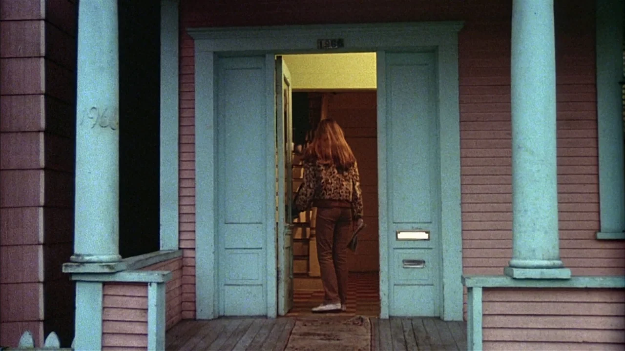 Ladies and Gentlemen, the Fabulous Stains (1985) movie still: medium — A pink house exterior features light teal columns and an open front door. A…