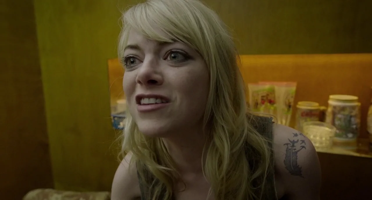 Birdman (2014) movie still: closeup — A dimly lit bar interior features yellow walls and shelf-mounted decorative mugs. A young woman with blonde…