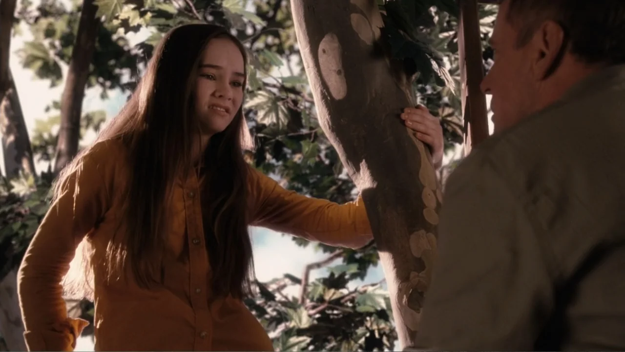 Flipped (2010) movie still: medium — A girl stands in the branches of a tree with lush green foliage surrounding her. She leans against the trunk…