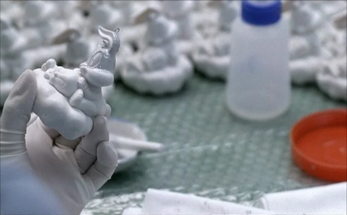Blissfully Yours (2002) movie still: closeup — A workbench in a factory displays rows of unpainted or partially painted rabbit figurines. A person…