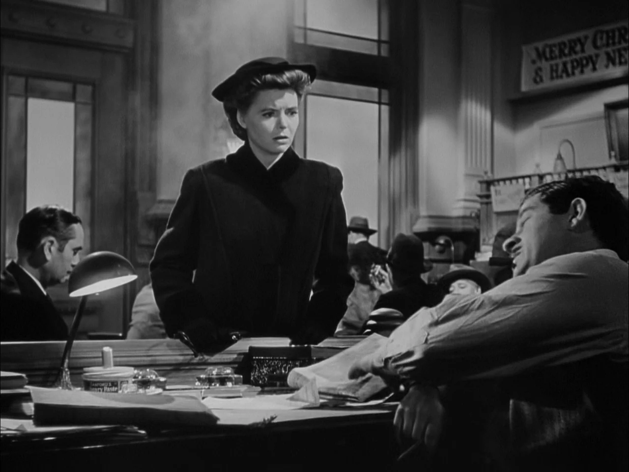 A Tree Grows In Brooklyn (1945) movie still: medium — A bustling 1940s newsroom filled with desks and papers under low-key lighting. A woman in a…